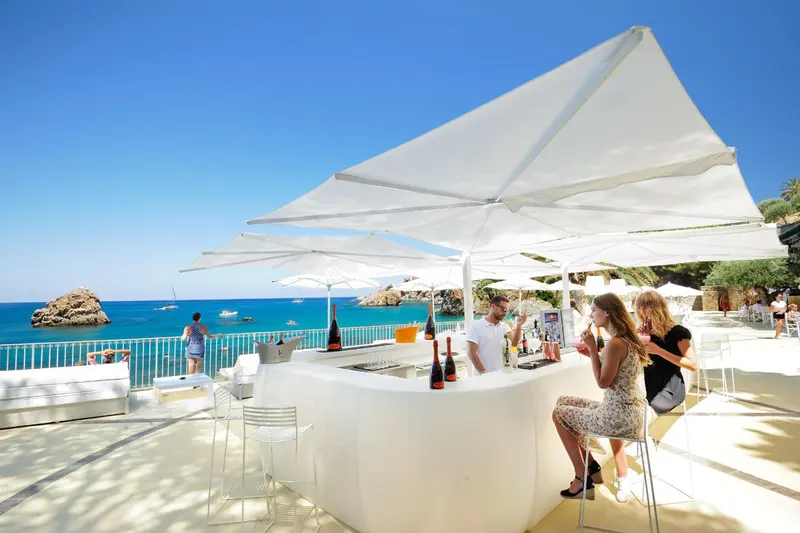 Un bar en plein air offre une vue sur la mer et les rochers.