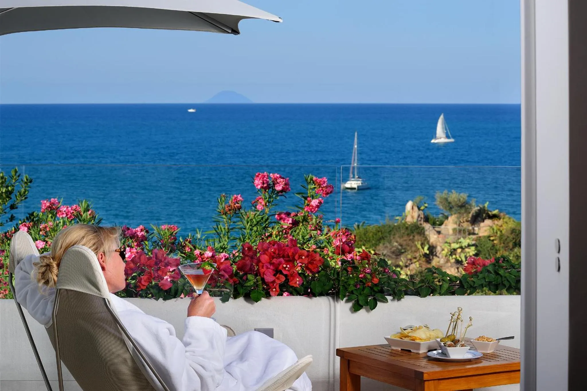 Une personne se détend sur une terrasse avec vue sur la mer.