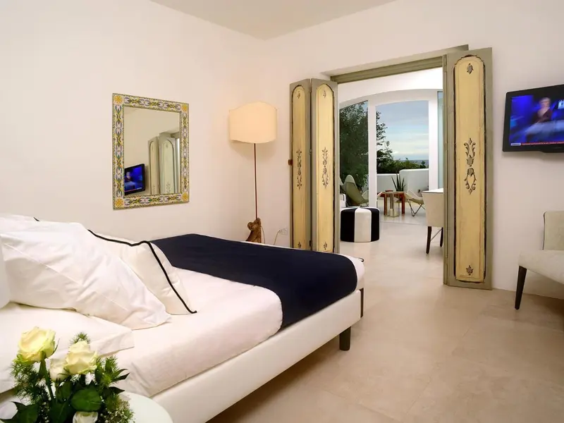 Une chambre lumineuse avec un grand lit et un accès sur une terrasse.