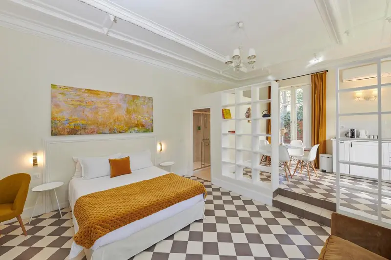 Une chambre lumineuse avec un lit recouvert d'une couverture orange et un sol à carreaux.