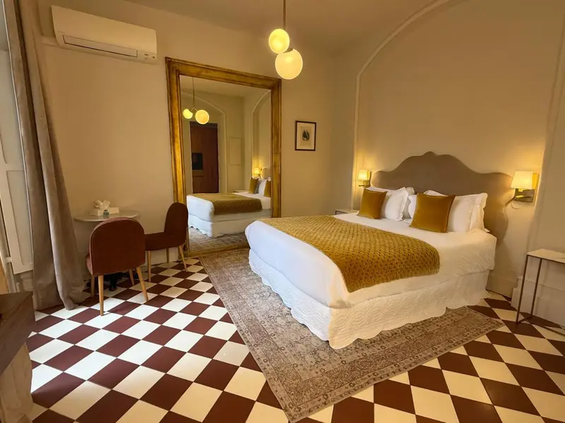 Une chambre à coucher lumineuse avec un grand lit et un miroir doré.