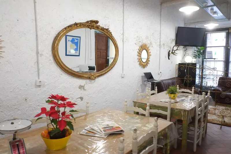 Une table et des chaises sont disposées devant un mur texturé orné de miroirs.