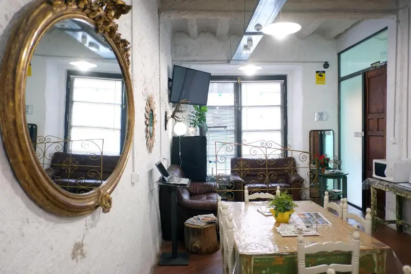 Une salle à manger lumineuse avec un grand miroir doré et des fenêtres.