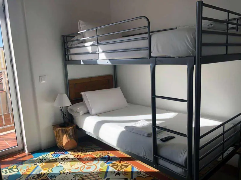 Une chambre avec des lits superposés et un tapis coloré.