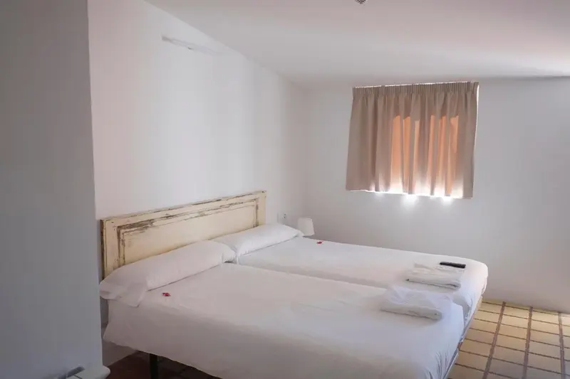 Une chambre lumineuse avec un lit double et une fenêtre.
