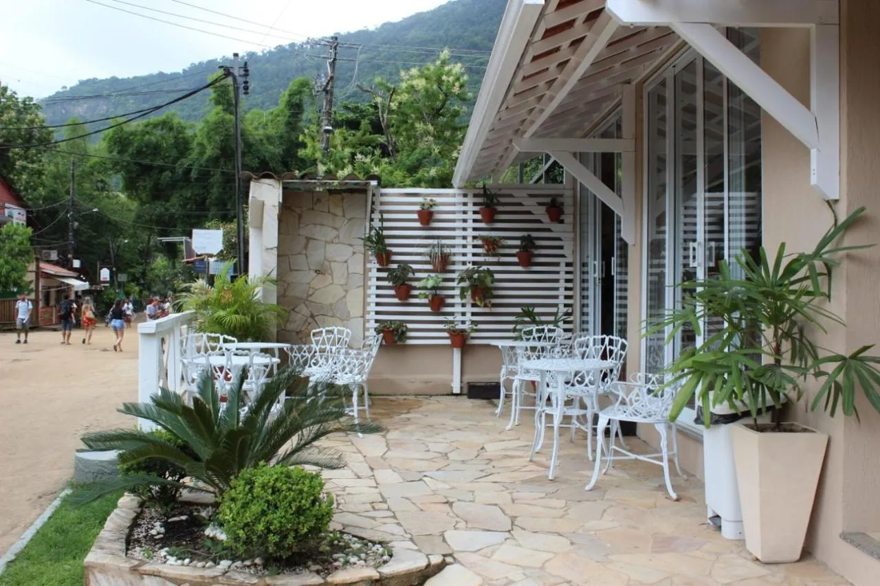 Terrasse ombragée avec tables et chaises en fer forgé devant un bâtiment.