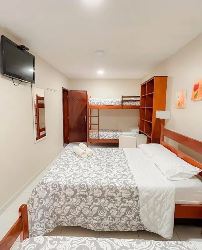 Une chambre avec lits superposés et un lit double est décorée de motifs floraux.
