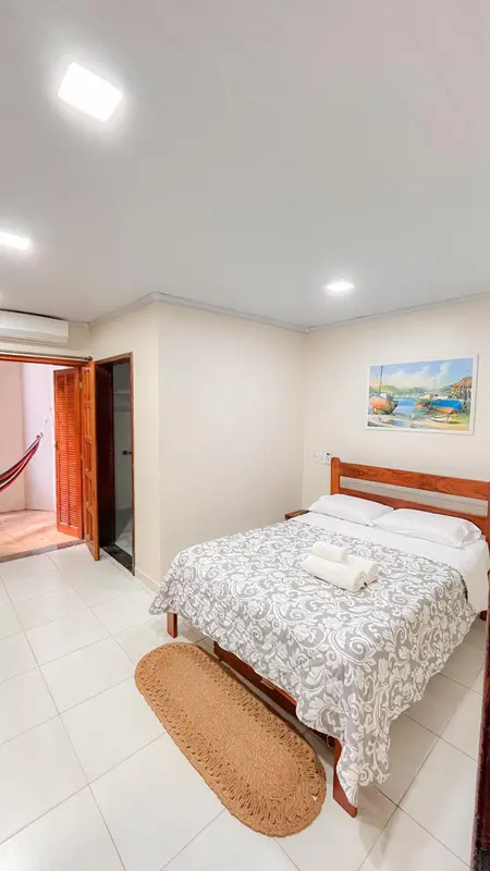 Une chambre lumineuse avec un grand lit et un hamac près de la porte.