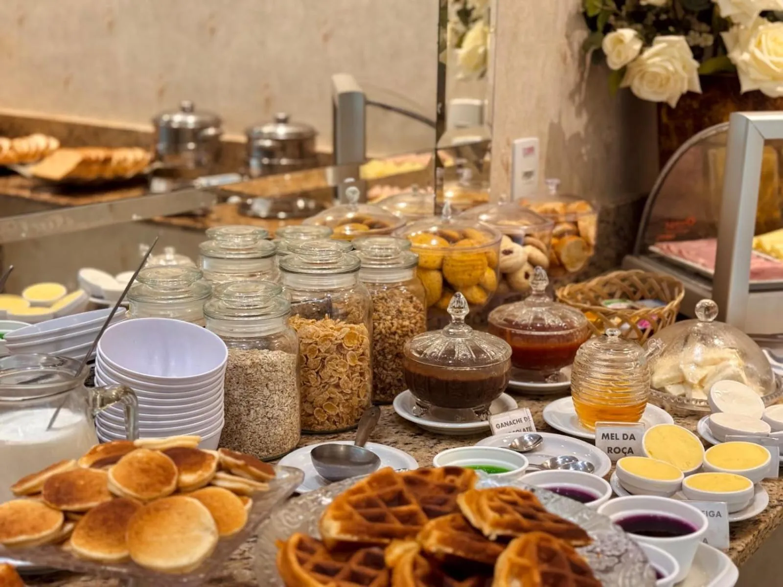 Un buffet propose une variété de pâtisseries, céréales et confitures.