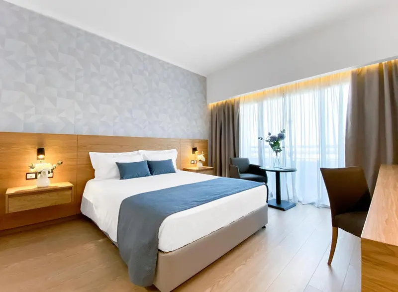 Une chambre lumineuse avec un grand lit et un coin salon.