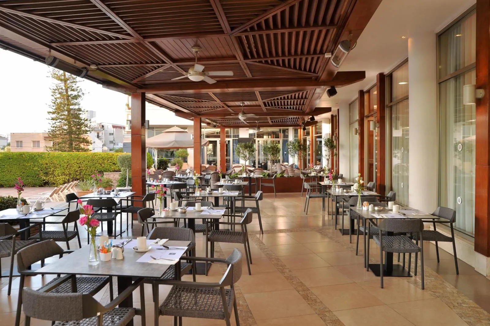 Terrasse ombragée avec tables et chaises pour les repas.
