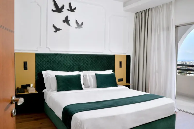 Une chambre lumineuse avec un grand lit recouvert d'une courtepointe verte et blanche.