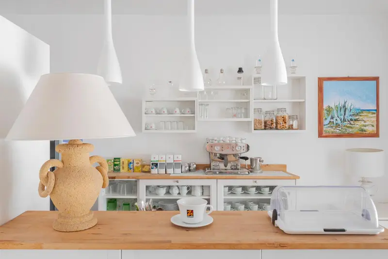 Une kitchenette lumineuse avec une machine à café et des tasses sur un comptoir en bois.