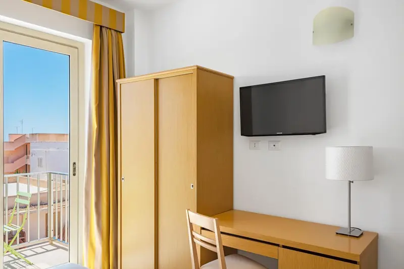 Une chambre lumineuse avec un bureau et un accès à un balcon.