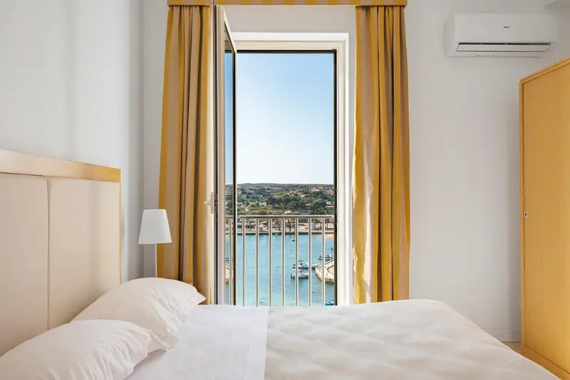 Une chambre lumineuse avec vue sur un port de plaisance.
