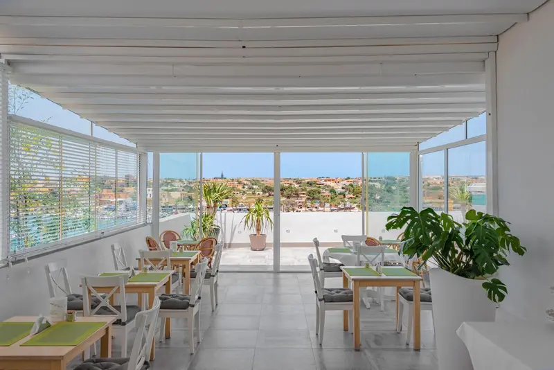 Une salle lumineuse s'ouvre sur une vue dégagée sur la mer et la ville.