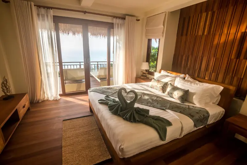 Une chambre avec un grand lit et un accès à une terrasse ensoleillée.