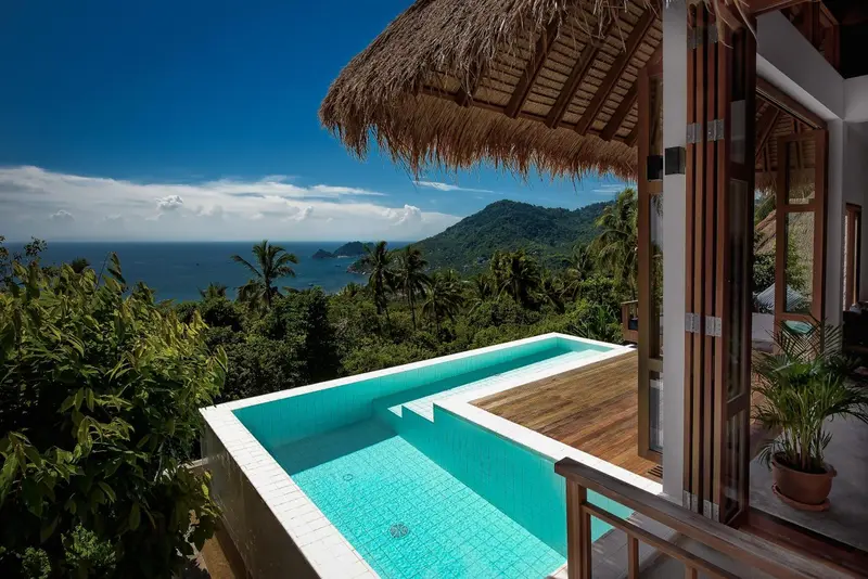 Une piscine turquoise offre une vue dégagée sur la mer et les collines verdoyantes.