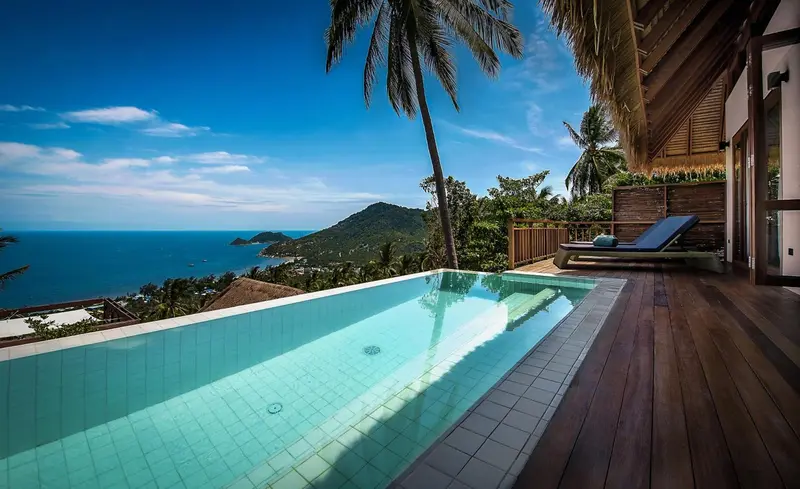 Une piscine à débordement offre une vue dégagée sur la mer et les collines environnantes.