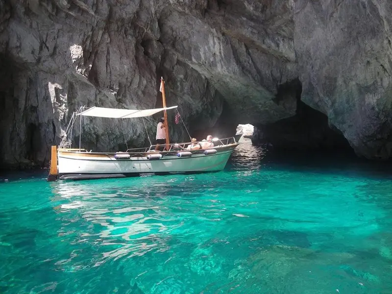 Un bateau à moteur navigue dans une crique aux eaux turquoise.
