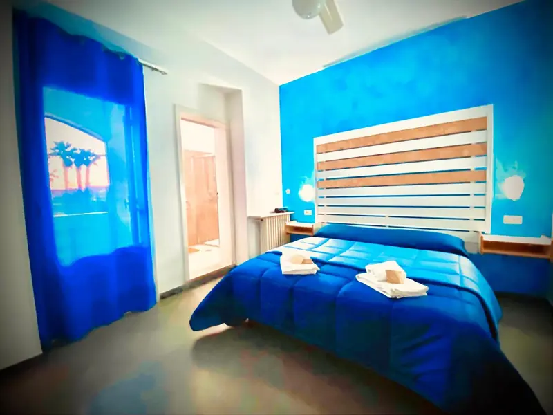 Une chambre bleue avec un grand lit et un rideau vif.