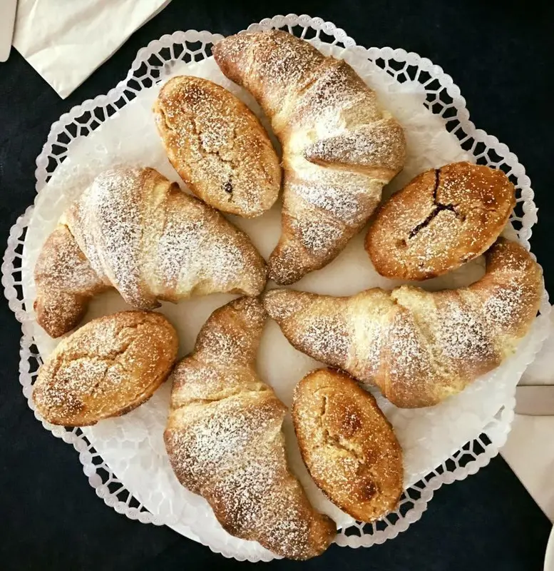 Assortiment de viennoiseries saupoudrées de sucre sur un plateau rond.