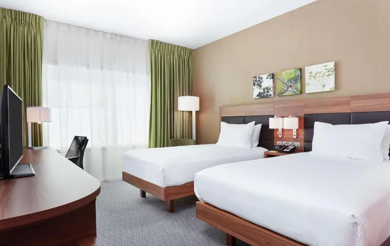 Une chambre d'hôtel avec deux lits simples et un bureau.