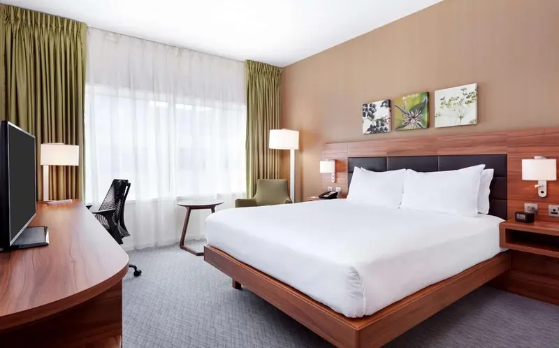 Une chambre d'hôtel lumineuse avec un grand lit et un bureau.