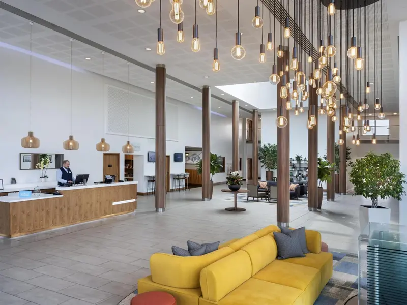 Vaste hall d'accueil lumineux avec un comptoir de réception et des espaces de détente.