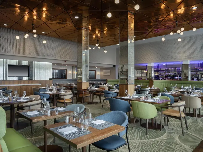 Une salle lumineuse avec des tables dressées pour un repas.