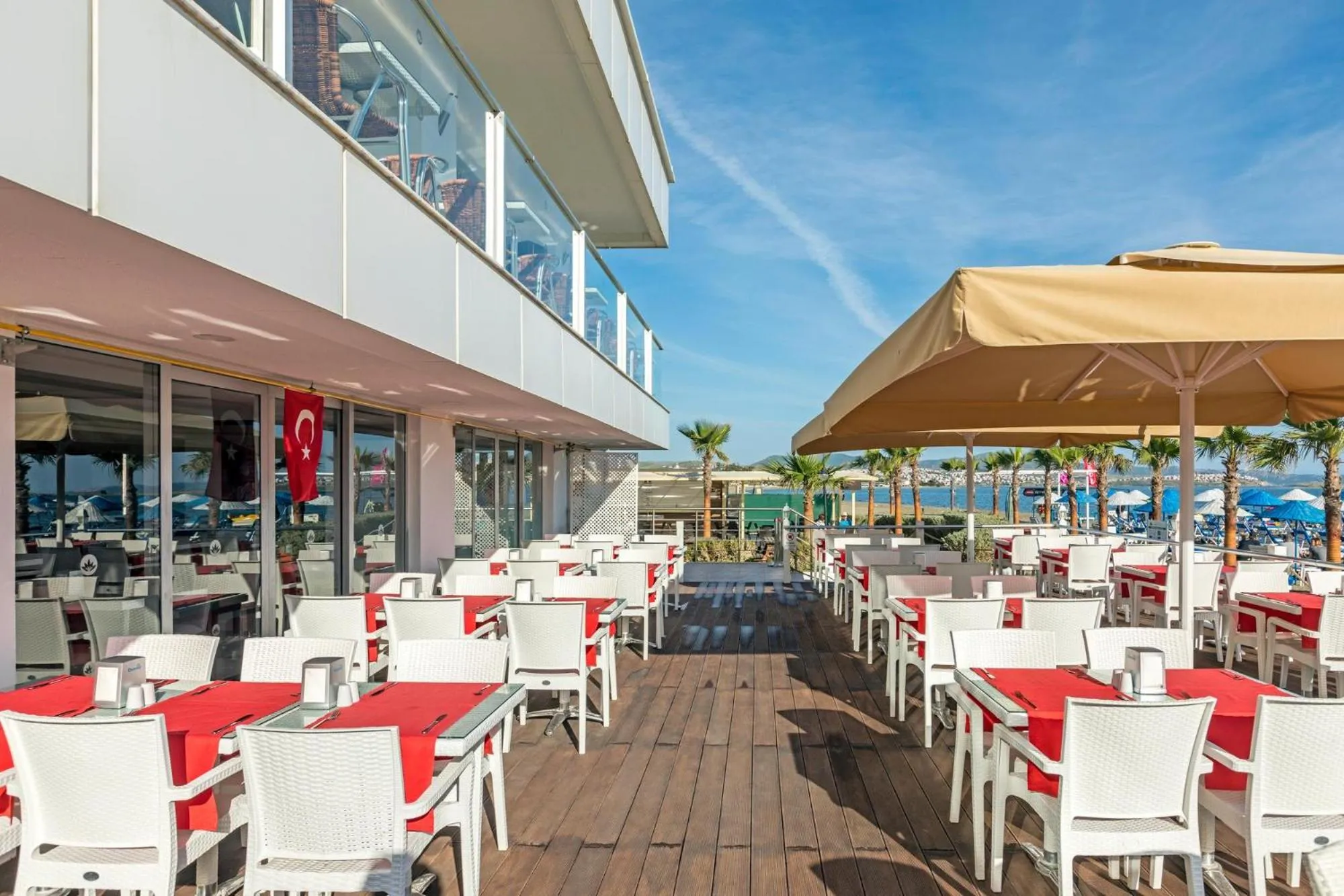 Terrasse de restaurant avec tables et parasols en bord de mer.