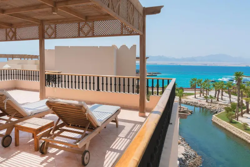 Terrasse avec transats donnant sur une vue mer et une végétation luxuriante.