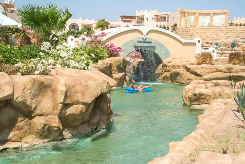Une personne se détend sur un flotteur dans un cours d'eau artificiel au sein d'un complexe hôtelier.