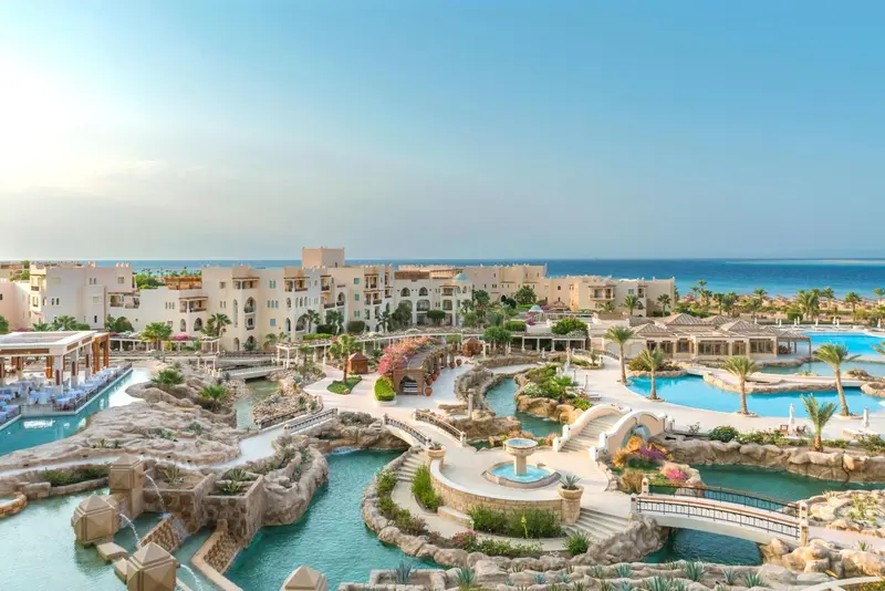 Vue aérienne d'un complexe hôtelier avec des piscines et des jardins.