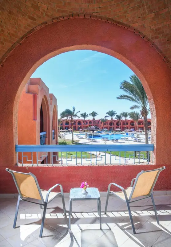 Vue sur une piscine et une végétation luxuriante depuis une terrasse.