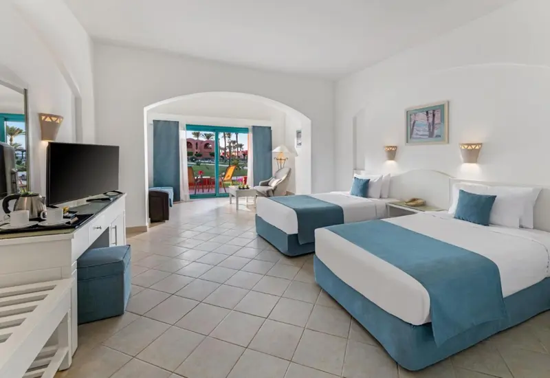Chambre lumineuse avec deux lits simples et vue sur une piscine.