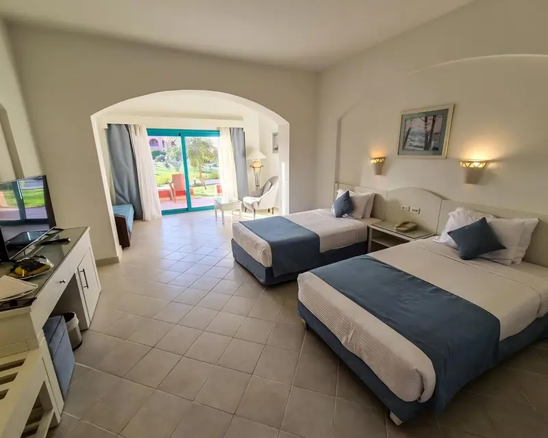 Chambre lumineuse avec deux lits simples et vue sur un jardin.