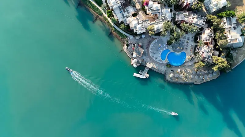 Vue aérienne d'un complexe hôtelier au bord de l'eau turquoise.