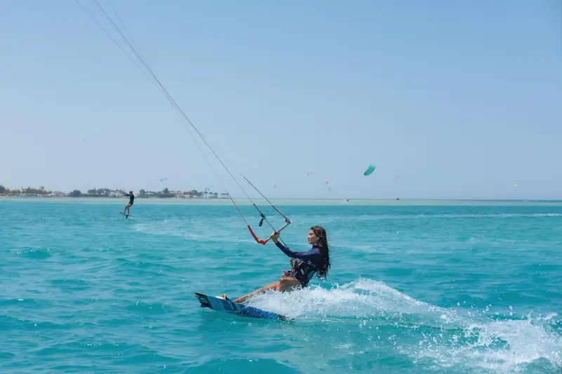 Une personne pratique le kitesurf sur une eau turquoise.