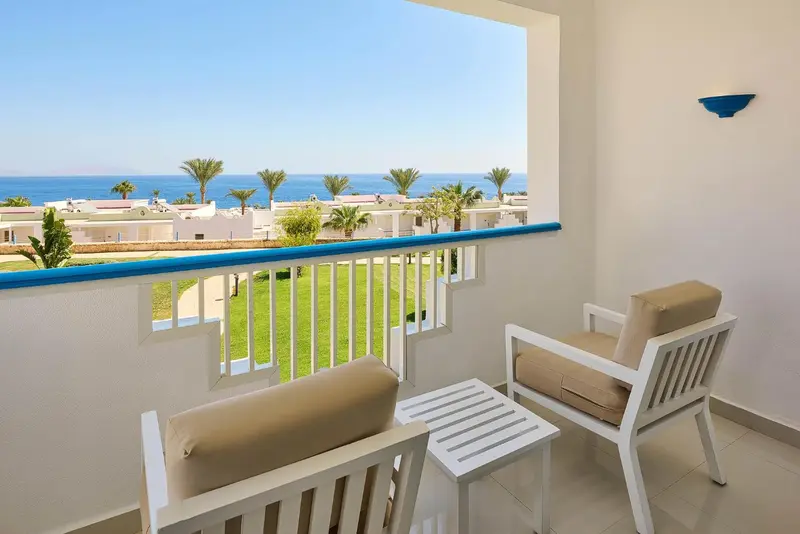 Terrasse avec mobilier d'extérieur donnant sur une vue mer et un jardin.