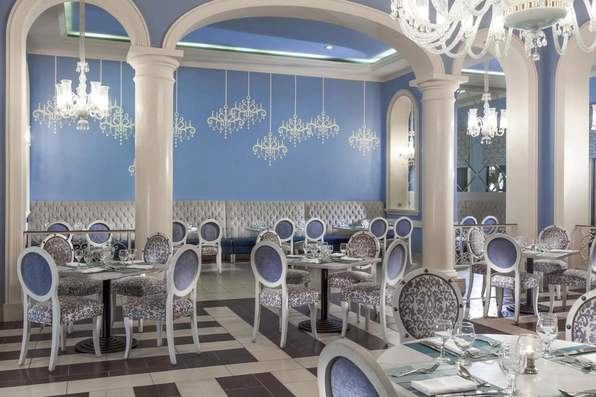 Une salle de restaurant lumineuse avec des tables dressées et des banquettes.