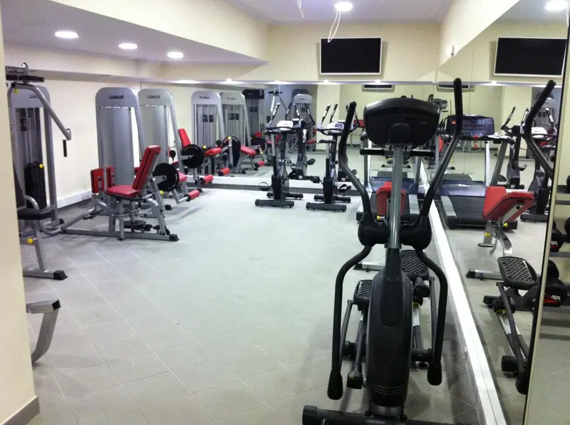 Une salle de sport lumineuse avec des équipements de musculation et des miroirs.