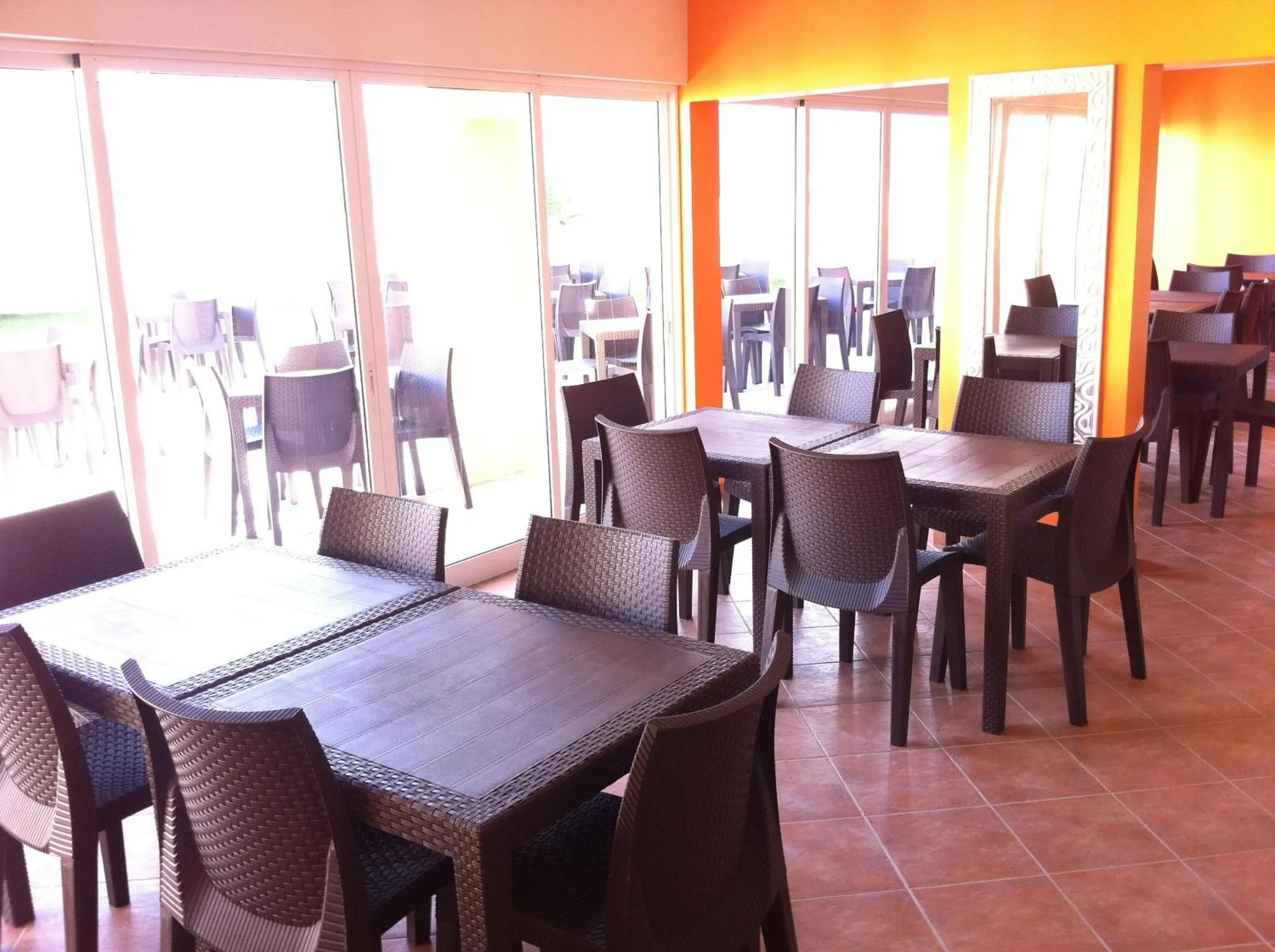 Une salle lumineuse avec des tables et des chaises en plastique.