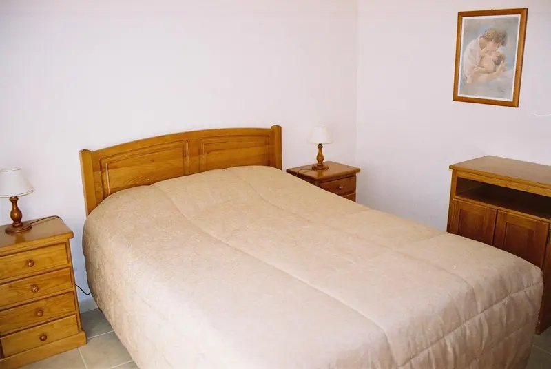 Une chambre lumineuse avec un grand lit recouvert d'une couverture.