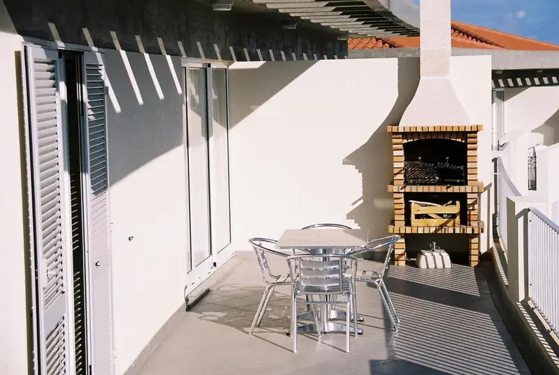 Terrasse avec mobilier de jardin et barbecue encastré.