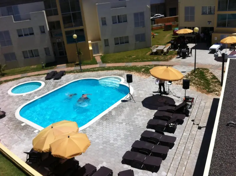 Une piscine rectangulaire entourée de chaises longues et de parasols jaunes.
