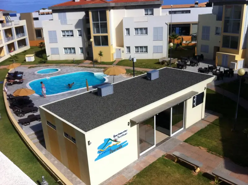 Vue aérienne d'un complexe avec piscine et bâtiments aux façades colorées.
