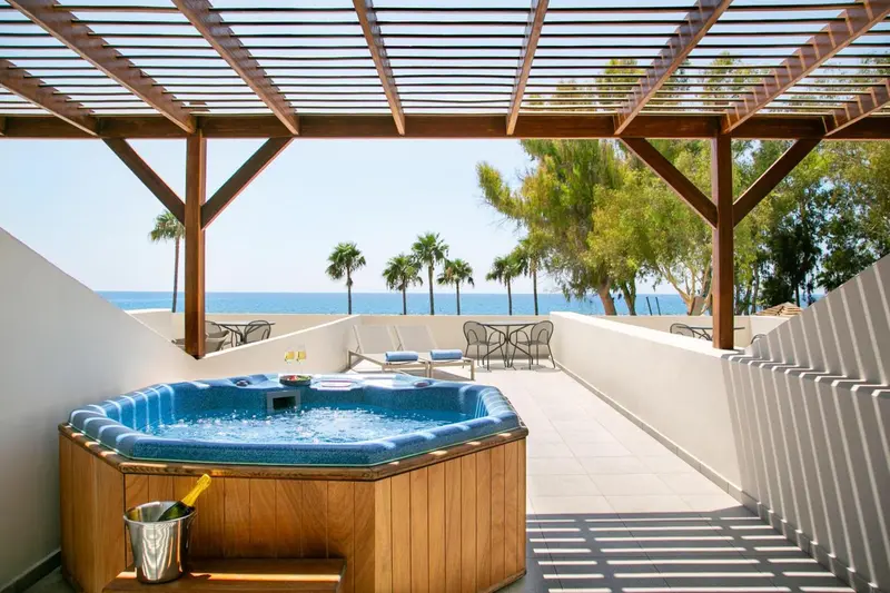 Un jacuzzi extérieur offre une vue sur la mer et la végétation luxuriante.