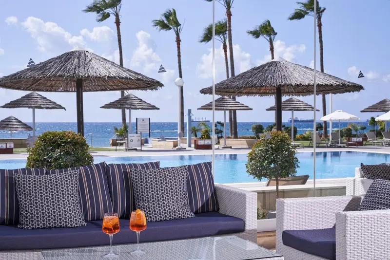 Mobilier d'extérieur avec des coussins rayés près d'une piscine et de parasols.