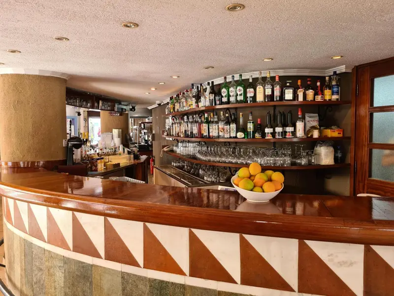 Un comptoir de bar en bois avec une sélection de bouteilles et des fruits frais.